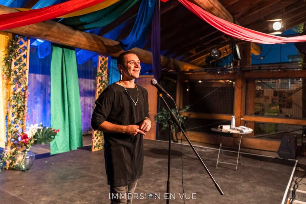 An individual stands at a microphone addressing participants during a networking speed dating session at the Vancouver Fringe Festival